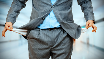 A person in a business suit pulling out empty pockets to represent bankruptcy